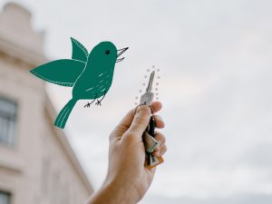 Eine Hand hält einen Wohnungsschlüssel in die Luft. Daneben fliegt ein gezeichneter Vogel.