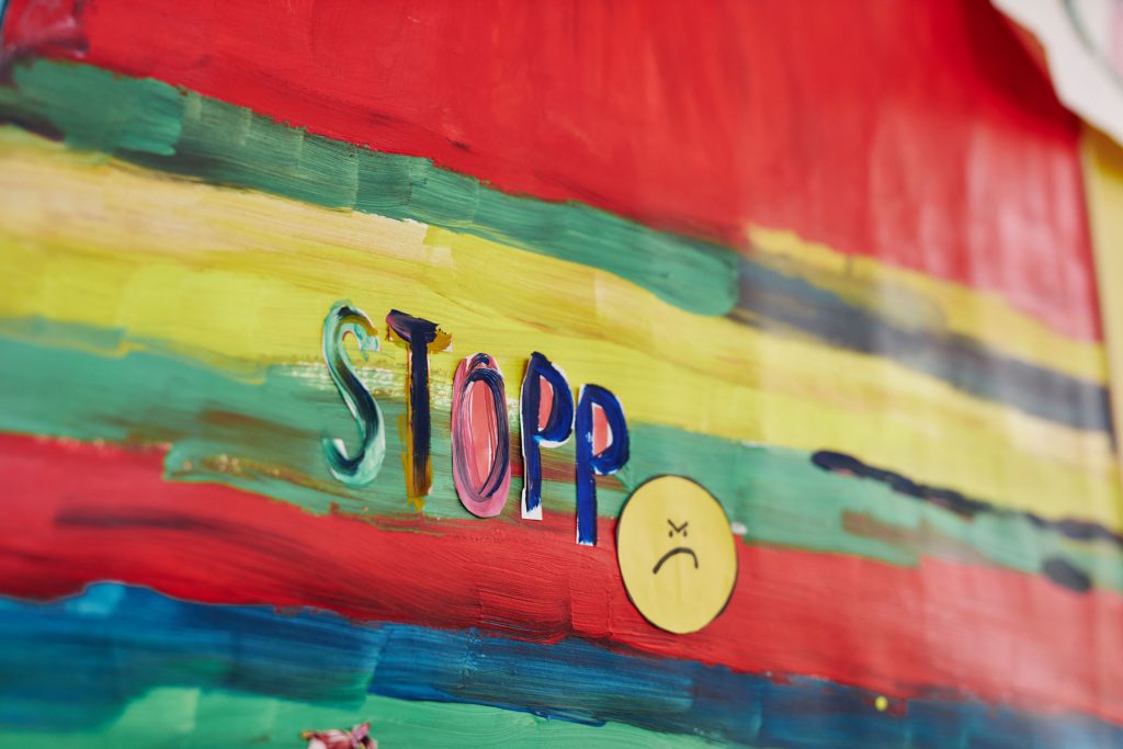 Eine Aufnahme von einem bunten Bild. In der Mitte steht "Stopp". Daneben ist ein ein trauriger Smiley.