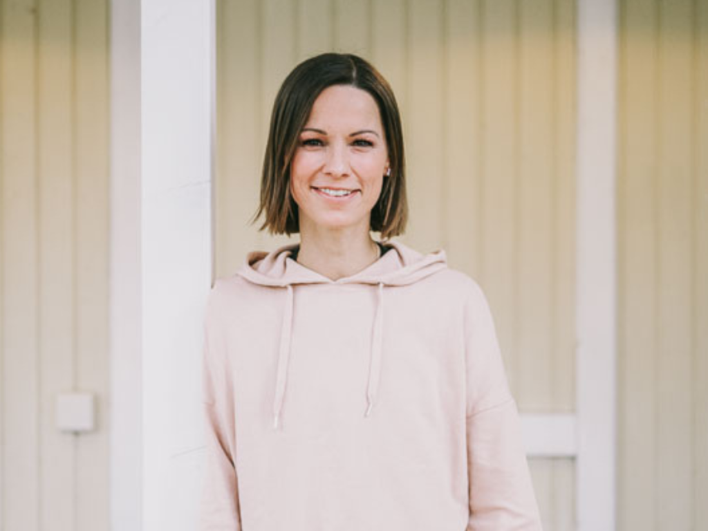 Christina Stürmer lächelt in die Kamera. Sie trägt einen beigen Pullover und hat kinnlange, braune Haare.