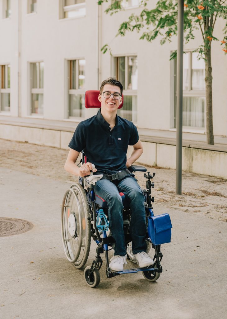 Vincent sitzt in einem Rollstuhl und lächelt in die Kamera.