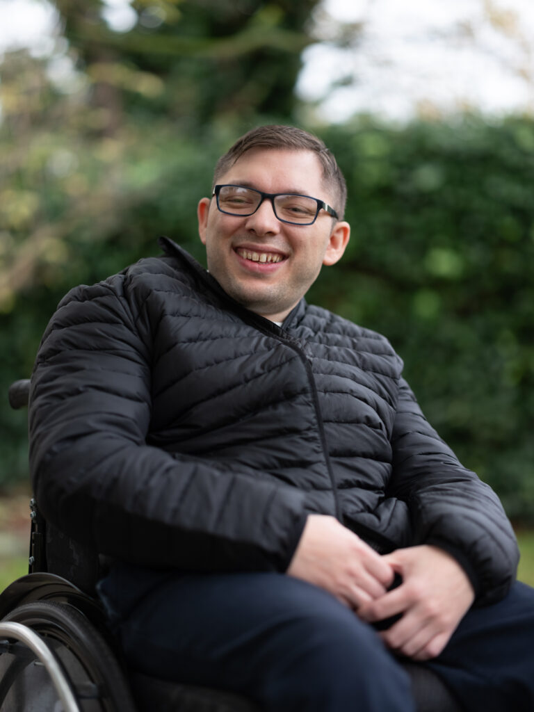 Lulzim Lushtaku schaut mit freundlichen Blick in die Kamera. Er trägt eine schwarze Winterjacke und trägt eine Brille.